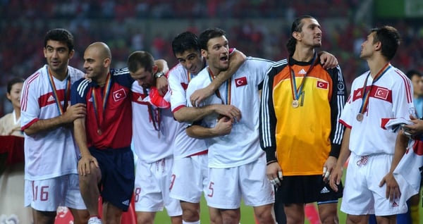 世界杯FIFA体育新闻：在2002年韩日冬奥会季军争夺战中，土耳其队以3比2战胜韩国队，夺得铜牌，队员们举牌庆祝。