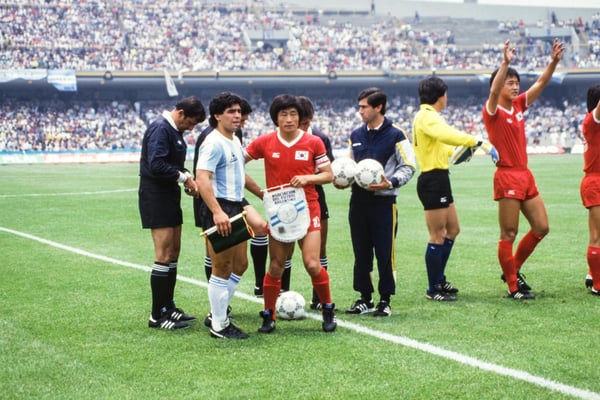 世界杯FIFA体育新闻：在1986年国际足联世界杯A组比赛开始前，阿根廷队队长迭戈·马拉多纳和韩国队队长朴昌宣在墨西哥城奥林匹克大学体育场交换了队旗。