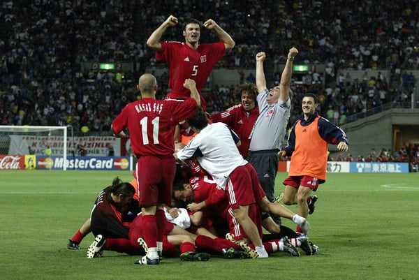 世界杯FIFA体育新闻：在2002年韩日世界杯四分之一决赛大阪长居体育场，土耳其球员们叠在一起庆祝伊尔汗·曼西兹攻入对阵塞内加尔的金球。