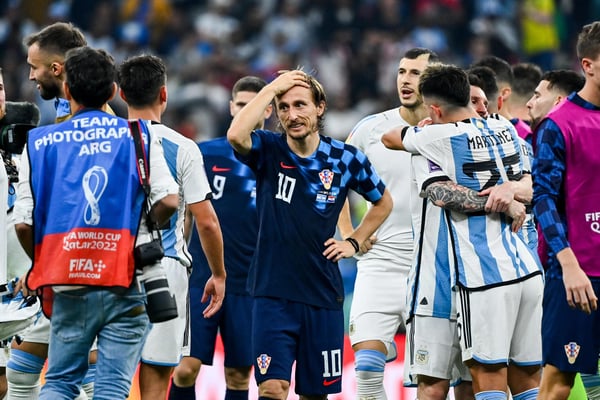 世界杯FIFA体育新闻：在2022年卡塔尔世界杯半决赛卢赛尔体育场，克罗地亚球员卢卡·莫德里奇神情沮丧，而阿根廷球员则在庆祝球队3-0战胜克罗地亚。