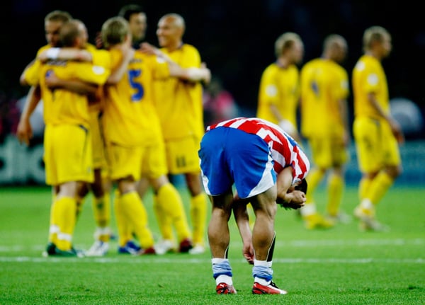 世界杯FIFA体育新闻：在2006年德国世界杯B组比赛中，巴拉圭球员罗伯托·阿库尼亚在柏林奥林匹克体育场，瑞典球员庆祝胜利的场景让他显得十分沮丧。