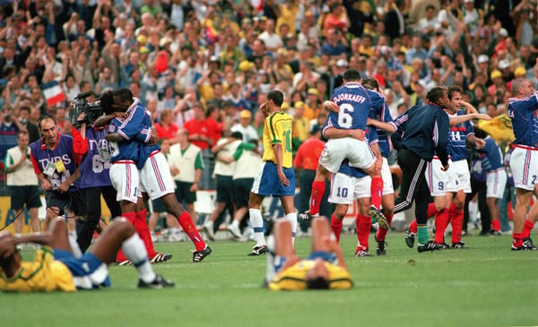 世界杯FIFA体育新闻：在圣丹尼斯法兰西体育场举行的1998年国际足联世界杯决赛后，法国队球员庆祝胜利，而巴西队球员则表现出极度沮丧。