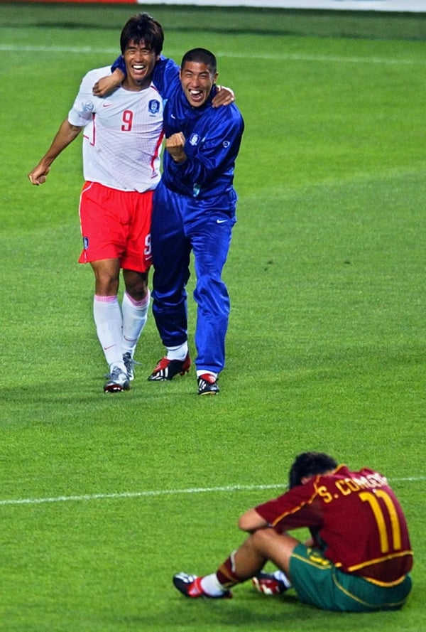 世界杯FIFA体育新闻：在2002年韩日世界杯D组比赛中，韩国队在仁川以1-0战胜葡萄牙队后，薛基贤庆祝胜利，而塞尔吉奥·孔塞桑则在一旁安慰。