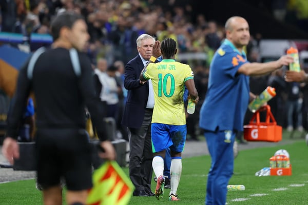 世界杯FIFA体育新闻：维尼修斯·儒尼奥尔在巴西对阵巴拉圭的比赛中与卡洛·安切洛蒂庆祝进球。