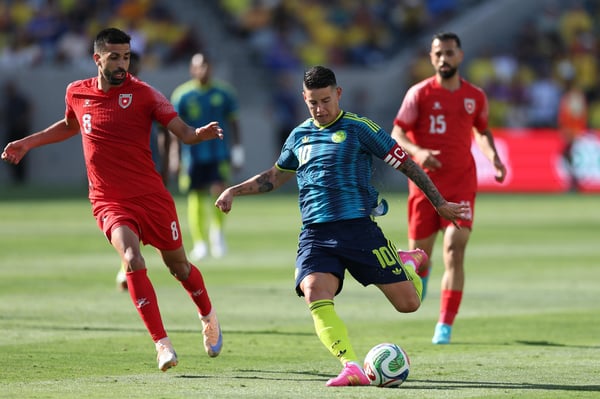 世界杯FIFA体育新闻：在约旦和哥伦比亚的国际友谊赛中，哥伦比亚球员詹姆斯·罗德里格斯射门，约旦球员努尔·阿尔-拉瓦布德试图拦截哥伦比亚球员。