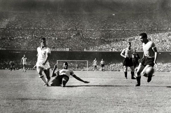 世界杯FIFA体育新闻：1950年7月16日，在里约热内卢马拉卡纳体育场举行的1950年世界杯决赛中，巴西前锋阿德米尔在乌拉圭后卫罗德里格斯·安德拉德的防守下仍然射门。最终乌拉圭以2比1战胜巴西。