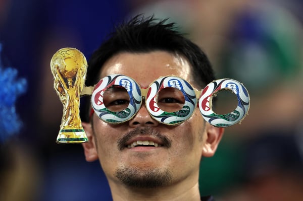 世界杯FIFA体育新闻：在2026年世界杯F组突尼斯对阵日本的比赛开始前，一位球迷戴着一副自制眼镜，以此纪念世界杯1000场比赛。