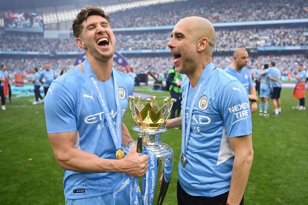 世界杯FIFA体育新闻:英格兰曼彻斯特 - 2022年5月22日:在2022年5月22日于英格兰曼彻斯特伊蒂哈德球场举行的英超联赛曼城对阵阿斯顿维拉的比赛中,曼城球员约翰·斯通斯和曼城主教练佩普·瓜迪奥拉在球队赢得英超联赛冠军后,与奖杯一同庆祝。(图片来源:Michael Regan/Getty Images)